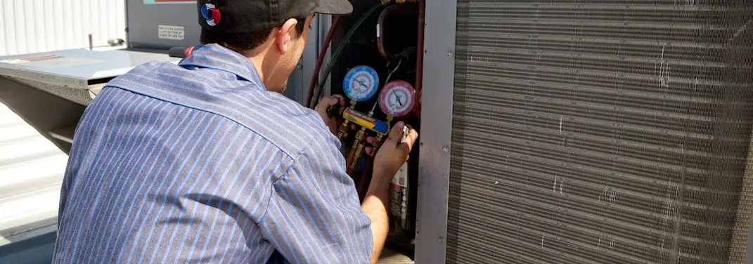 HVAC technician servicing a condenser unit in Middle Valley